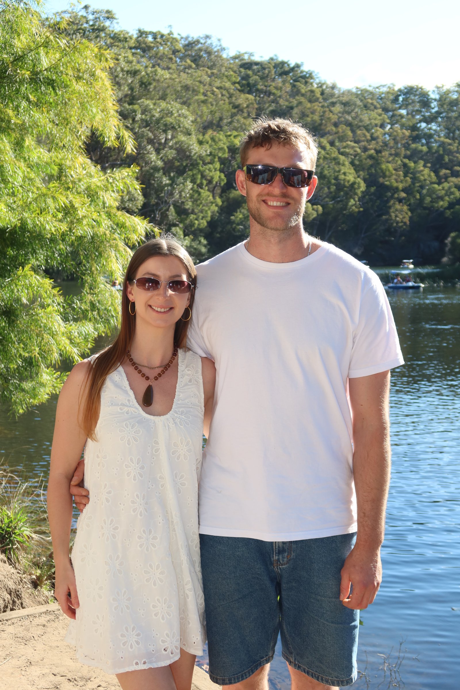 Jess and Nolan standing together beside the water